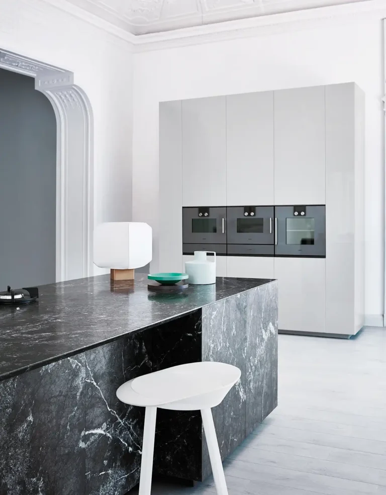 Cuisine sur mesure avec armoires blanches et ilot en pierre et 3 fours Gaggenau chez April Moon et son électroménager pour sa cuisine sur mesure