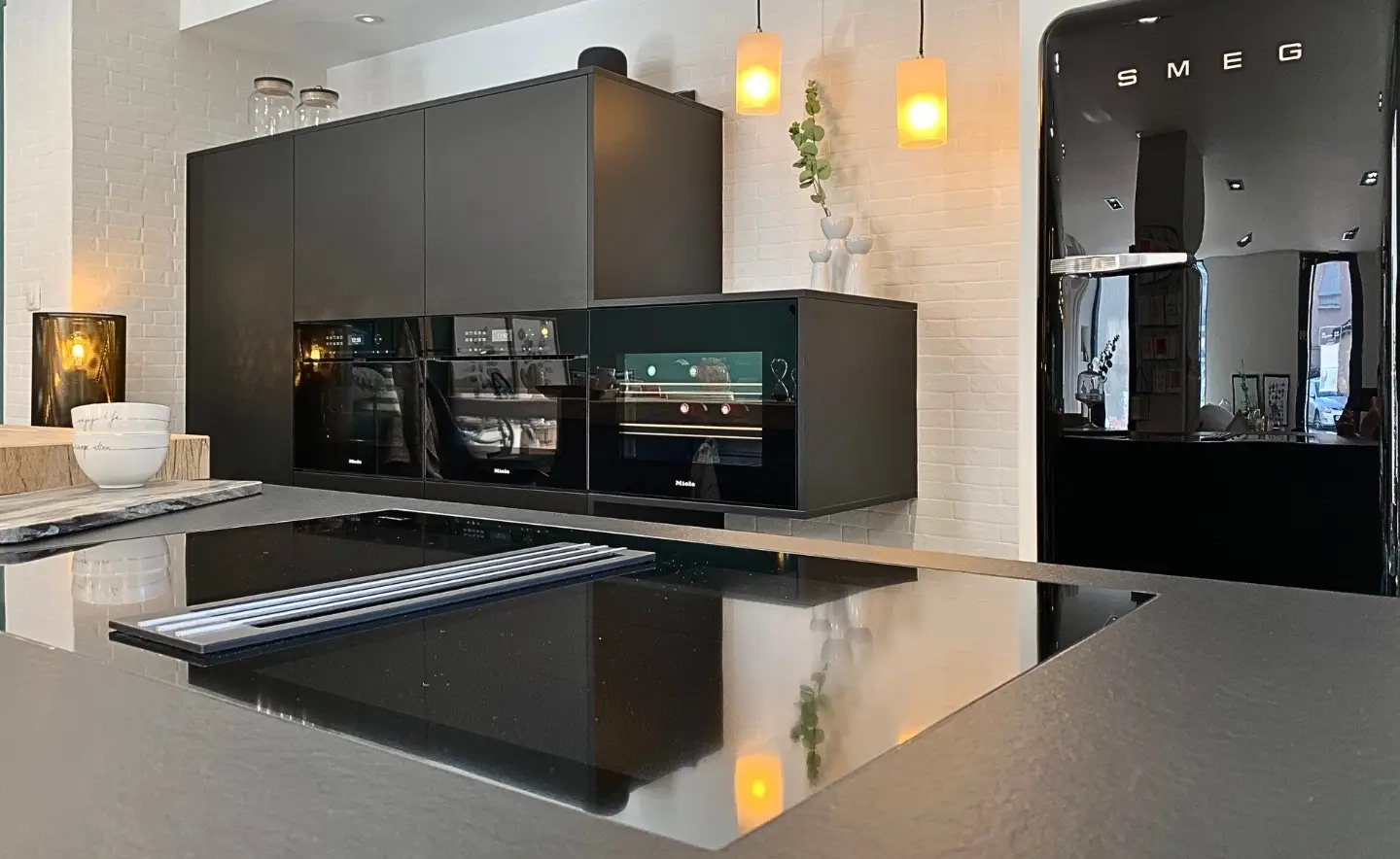 Magasin April Moon Home à Craponne proche de Lyon avec une cuisine sur mesure et moderne noir avec une cave à vin Miele, une plaque de cuisson aspirante Miele, deux fours Miele et un réfrigérateur Smeg